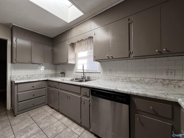 kitchen with gray cabinetry, decorative backsplash, stainless steel dishwasher, light tile patterned flooring, and a sink