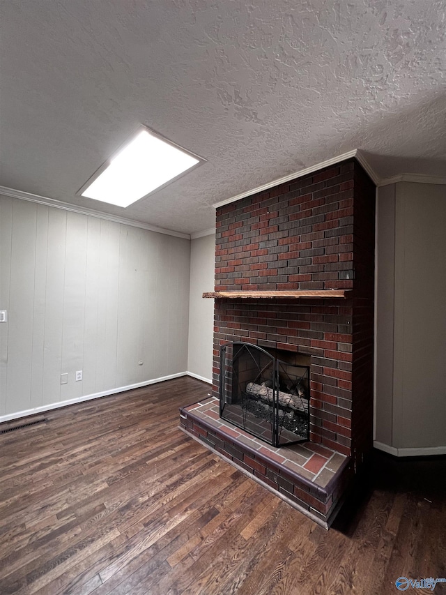 unfurnished living room featuring a textured ceiling, wood finished floors, a fireplace, and ornamental molding