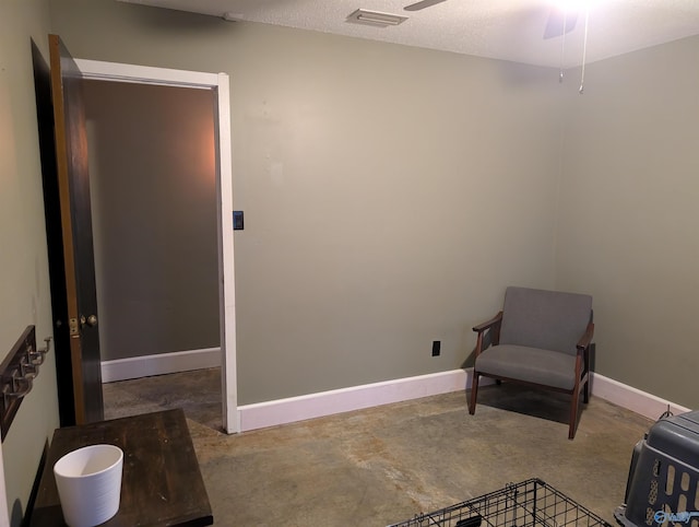 living area with ceiling fan, a textured ceiling, and concrete floors