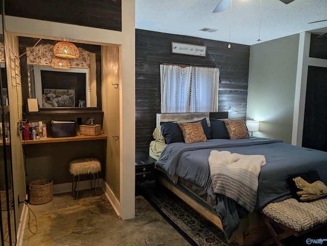 bedroom with ceiling fan, wood walls, a textured ceiling, and concrete floors