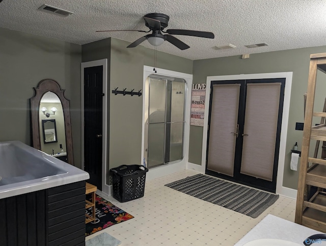 interior space featuring a textured ceiling, vanity, an enclosed shower, and ceiling fan