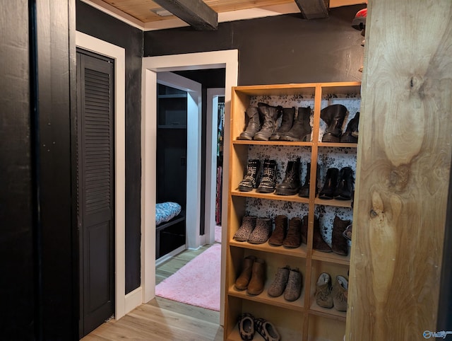 walk in closet featuring beam ceiling and light hardwood / wood-style flooring