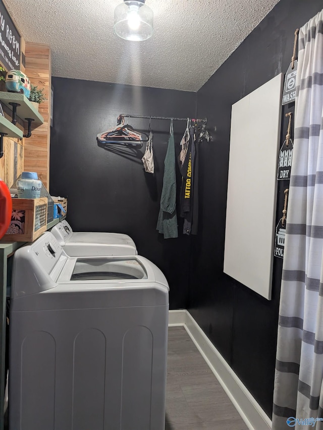 washroom with hardwood / wood-style floors, washer and dryer, and a textured ceiling