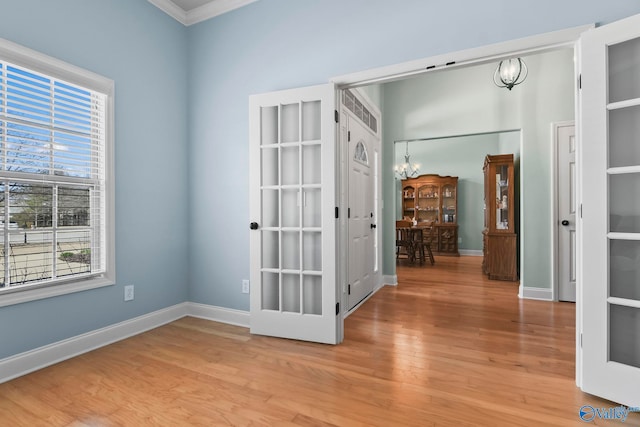 unfurnished room with baseboards, an inviting chandelier, and light wood finished floors