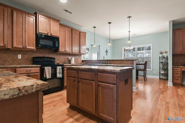 kitchen with a sink, light wood-type flooring, tasteful backsplash, and black appliances