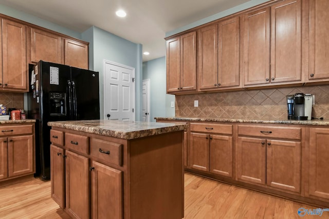 kitchen with stone counters, decorative backsplash, light wood-style flooring, and brown cabinetry