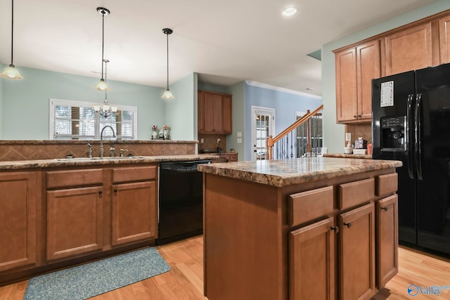 kitchen with light wood finished floors, backsplash, stone countertops, black appliances, and a sink