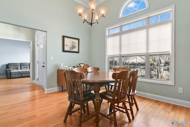 dining space with light wood-style flooring, an inviting chandelier, and baseboards