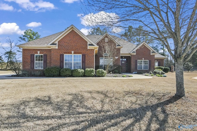 view of front of property with brick siding, roof with shingles, and a front lawn