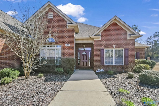 traditional-style house featuring brick siding and a shingled roof