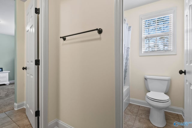 bathroom with tile patterned floors, baseboards, toilet, and shower / bath combo