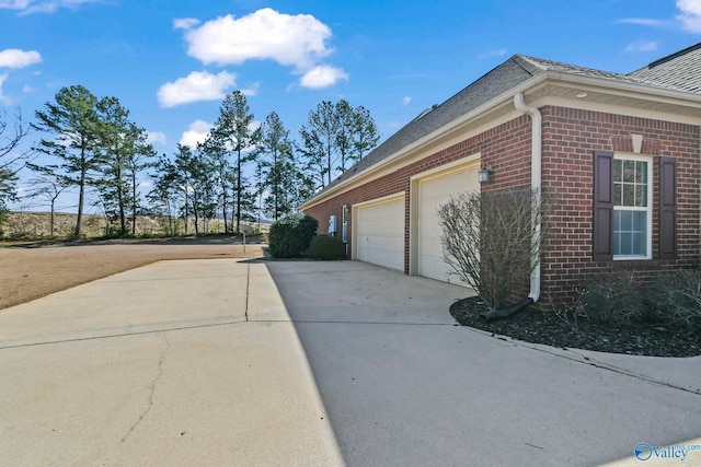 view of property exterior featuring a garage, brick siding, and concrete driveway