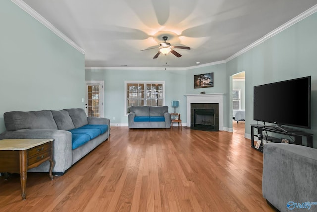 living room with baseboards, a wealth of natural light, a fireplace, light wood-style floors, and a ceiling fan