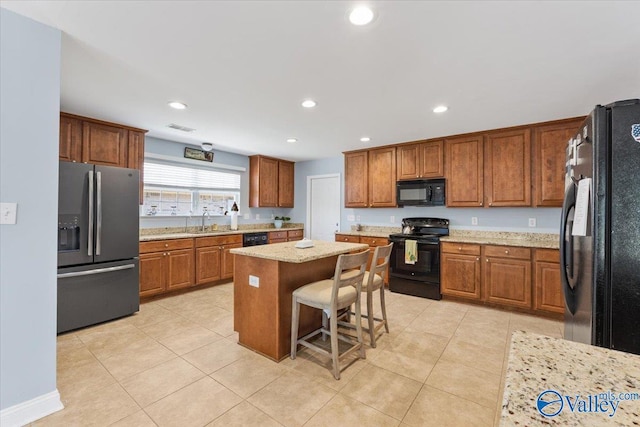 kitchen featuring visible vents, brown cabinets, a sink, black appliances, and recessed lighting