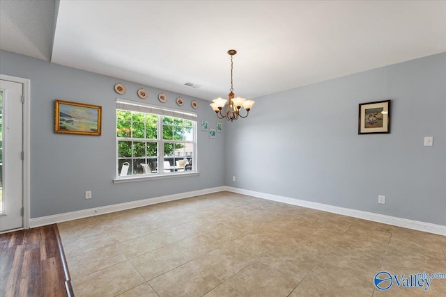spare room featuring baseboards, visible vents, and a chandelier