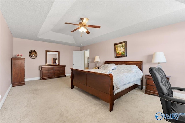 bedroom featuring baseboards, a ceiling fan, a tray ceiling, and light colored carpet