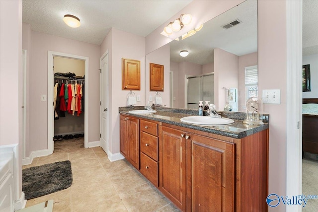 full bathroom with visible vents, a sink, a stall shower, and double vanity