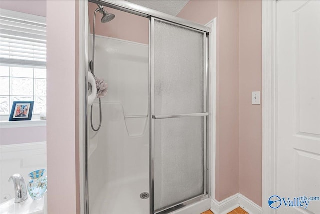 bathroom with baseboards and a shower stall