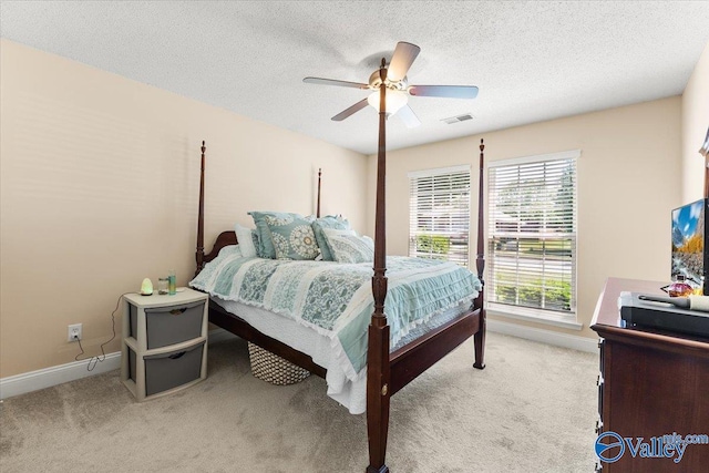 carpeted bedroom with baseboards, a ceiling fan, a textured ceiling, and visible vents