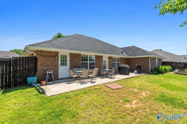 rear view of property featuring a fenced backyard, a patio, a yard, and brick siding