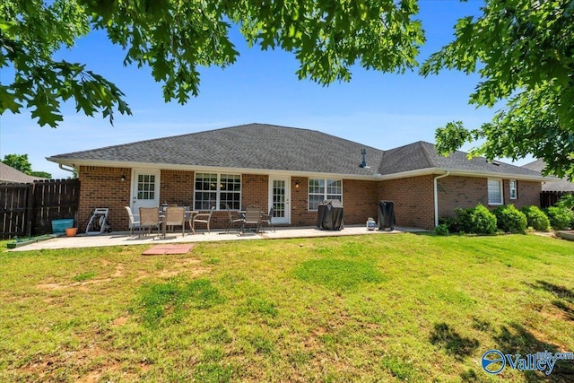 rear view of house with a yard, brick siding, fence, and a patio area