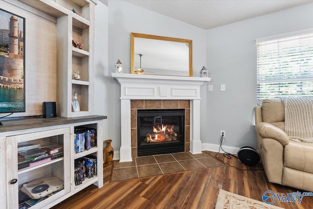living area with dark wood-style flooring and a tile fireplace