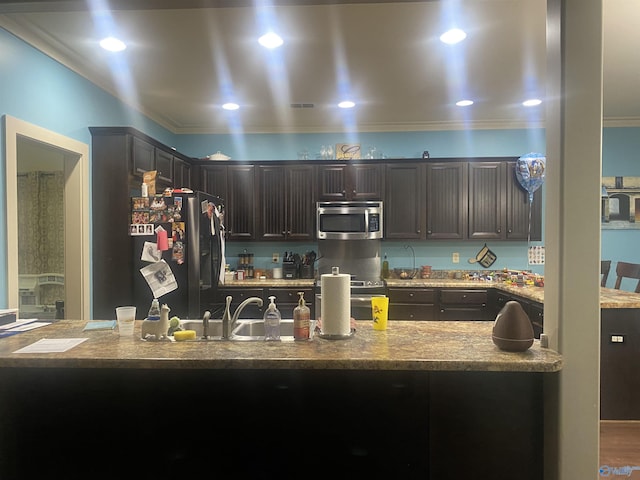 kitchen with light stone counters, recessed lighting, appliances with stainless steel finishes, and ornamental molding