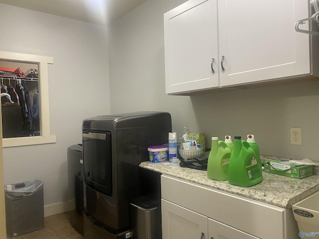 clothes washing area featuring cabinet space, baseboards, and separate washer and dryer