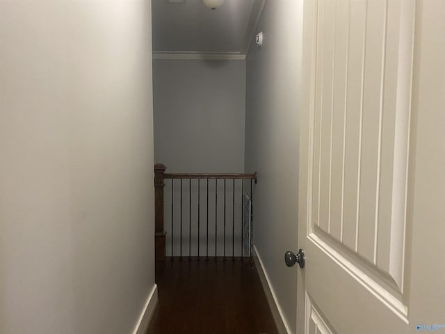 hall featuring an upstairs landing, baseboards, crown molding, and dark wood-type flooring