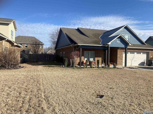 view of front of house with brick siding, a front lawn, fence, a garage, and driveway