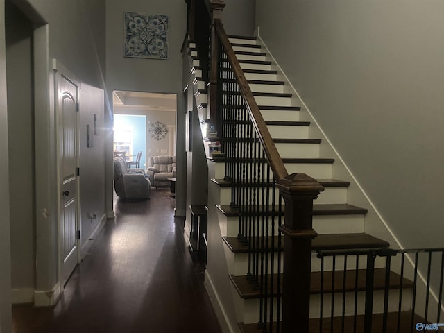 staircase with wood finished floors and a towering ceiling
