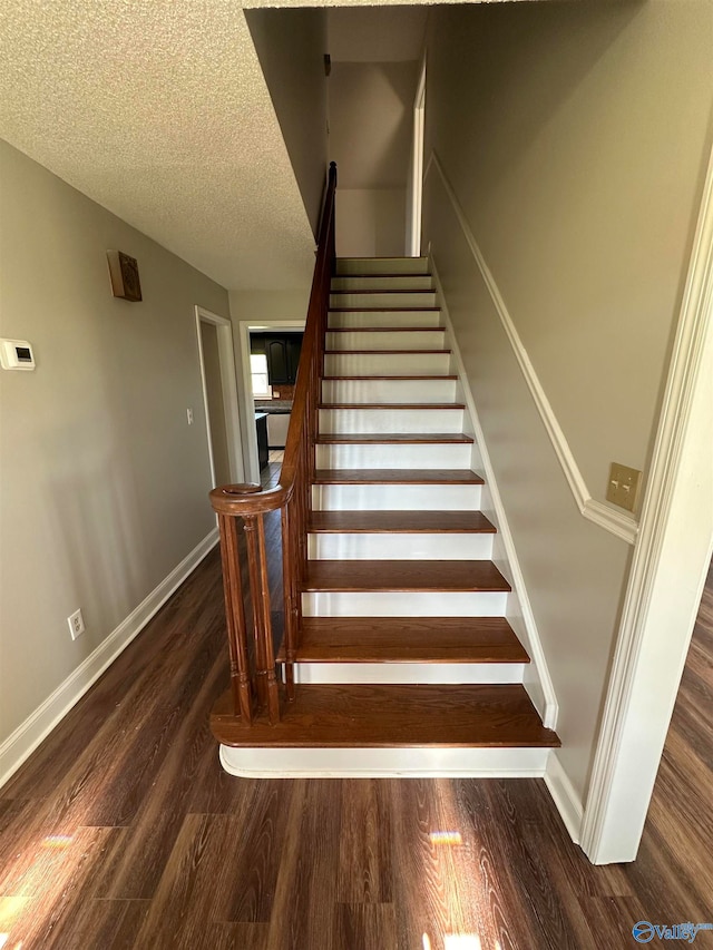 staircase featuring wood-type flooring and a textured ceiling