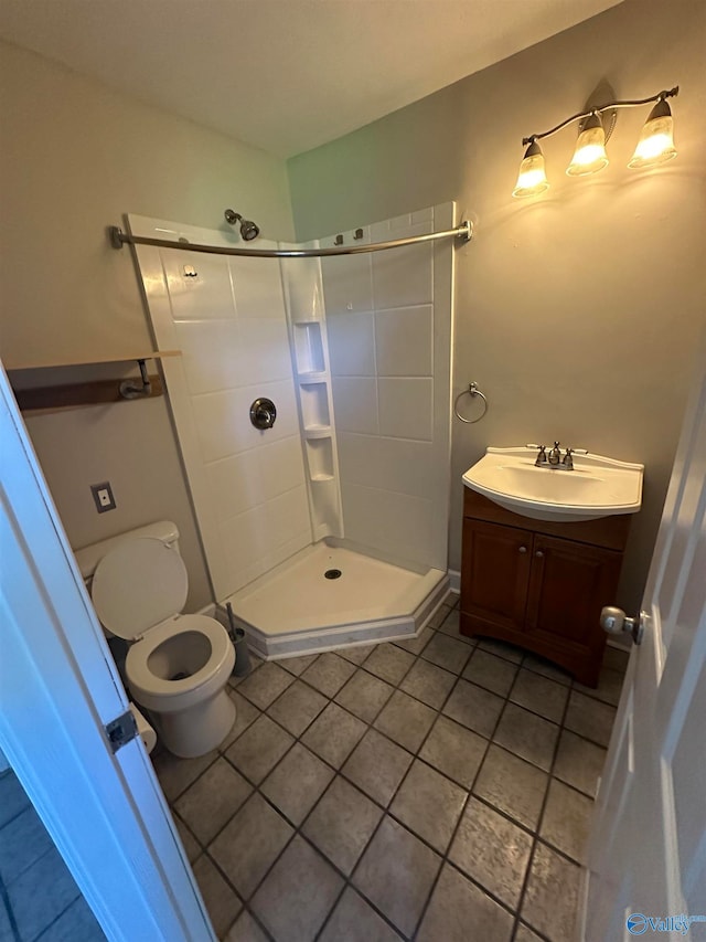 bathroom featuring tile patterned flooring, vanity, toilet, and walk in shower