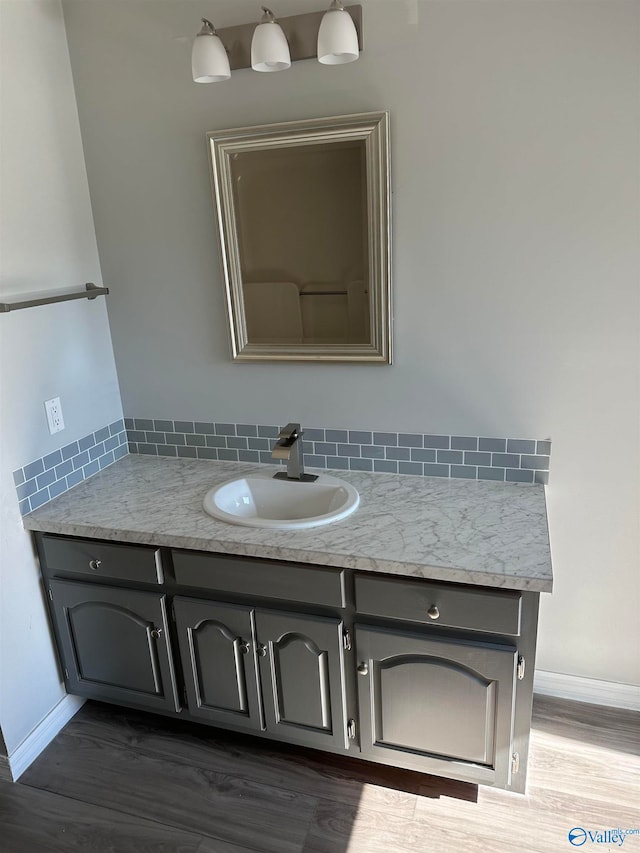 bathroom featuring hardwood / wood-style floors, vanity, and decorative backsplash