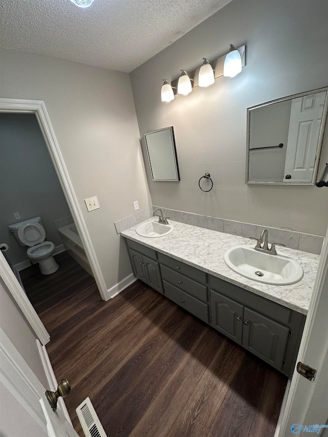 bathroom featuring hardwood / wood-style floors, vanity, a textured ceiling, and toilet