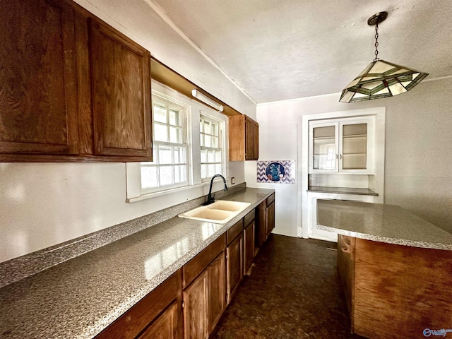 kitchen with sink, hanging light fixtures, light stone counters, and a textured ceiling