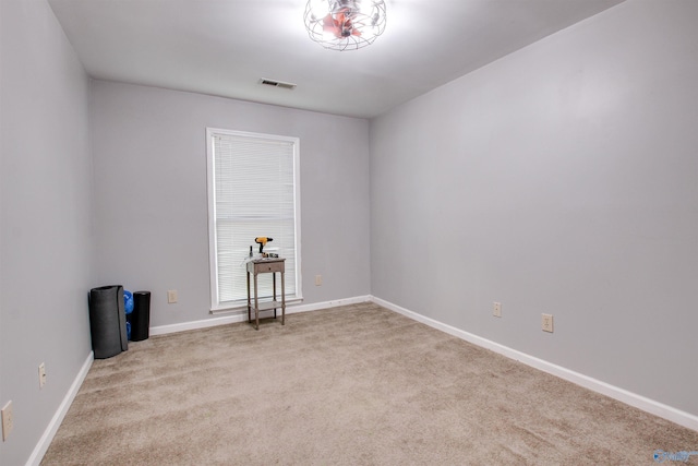 unfurnished room with carpet, visible vents, and baseboards