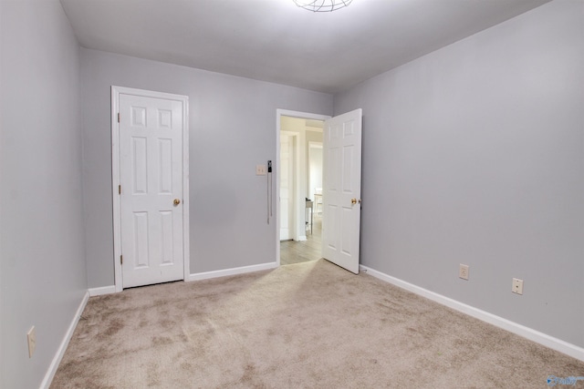 unfurnished bedroom featuring light carpet and baseboards