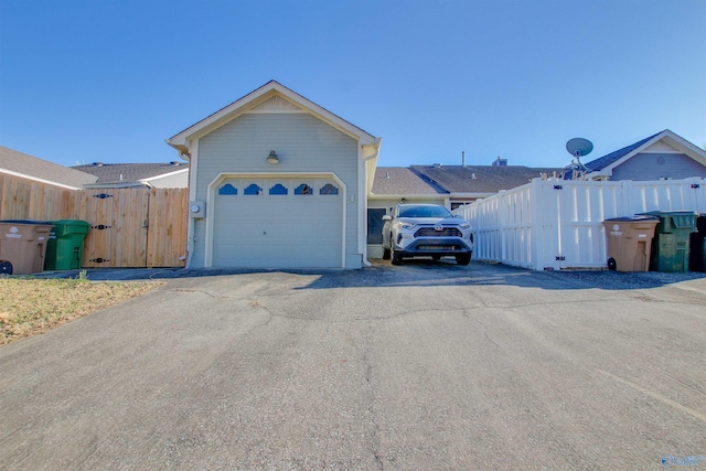 exterior space featuring driveway, a garage, and fence