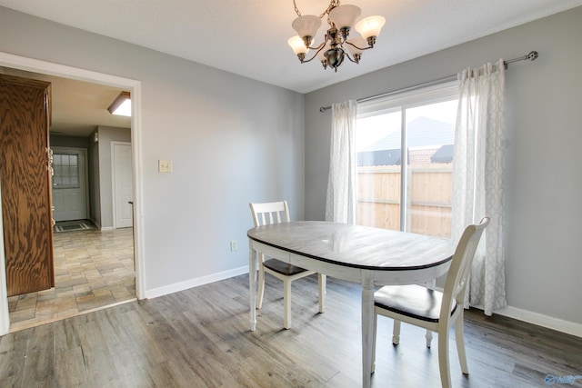 dining area featuring light wood-style floors, baseboards, and a chandelier