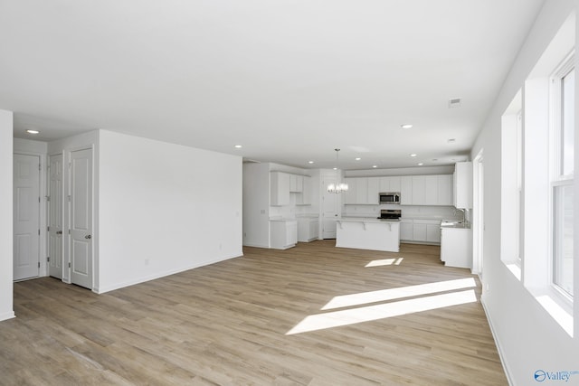 unfurnished living room with light hardwood / wood-style floors and a chandelier