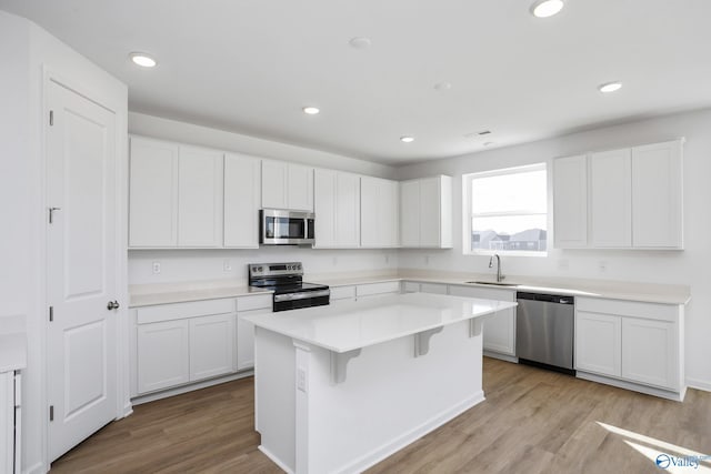 kitchen featuring sink, white cabinetry, light wood-type flooring, appliances with stainless steel finishes, and a kitchen island