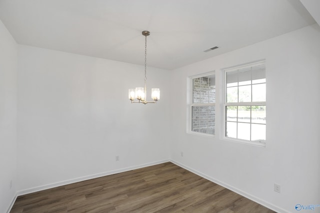 empty room with dark hardwood / wood-style floors and a notable chandelier