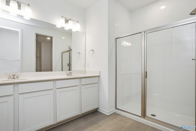 bathroom with a shower with door, vanity, and tile patterned flooring