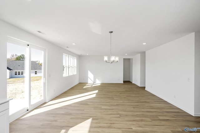 unfurnished dining area with an inviting chandelier and light wood-type flooring