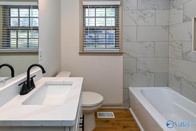 bathroom with baseboards, visible vents, toilet, wood finished floors, and vanity