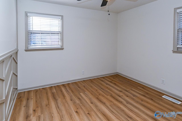 unfurnished room featuring light wood finished floors, baseboards, visible vents, and a ceiling fan