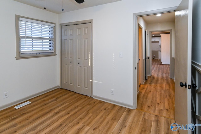 unfurnished bedroom with a closet, visible vents, baseboards, and light wood finished floors