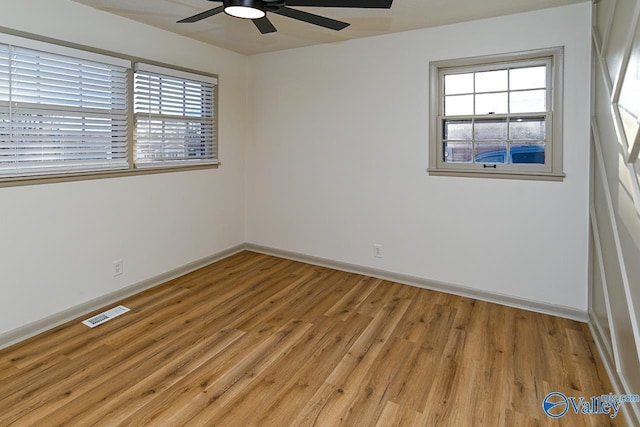 empty room with light wood finished floors, baseboards, visible vents, and a wealth of natural light