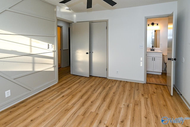 unfurnished bedroom with light wood-type flooring, a closet, a sink, and baseboards